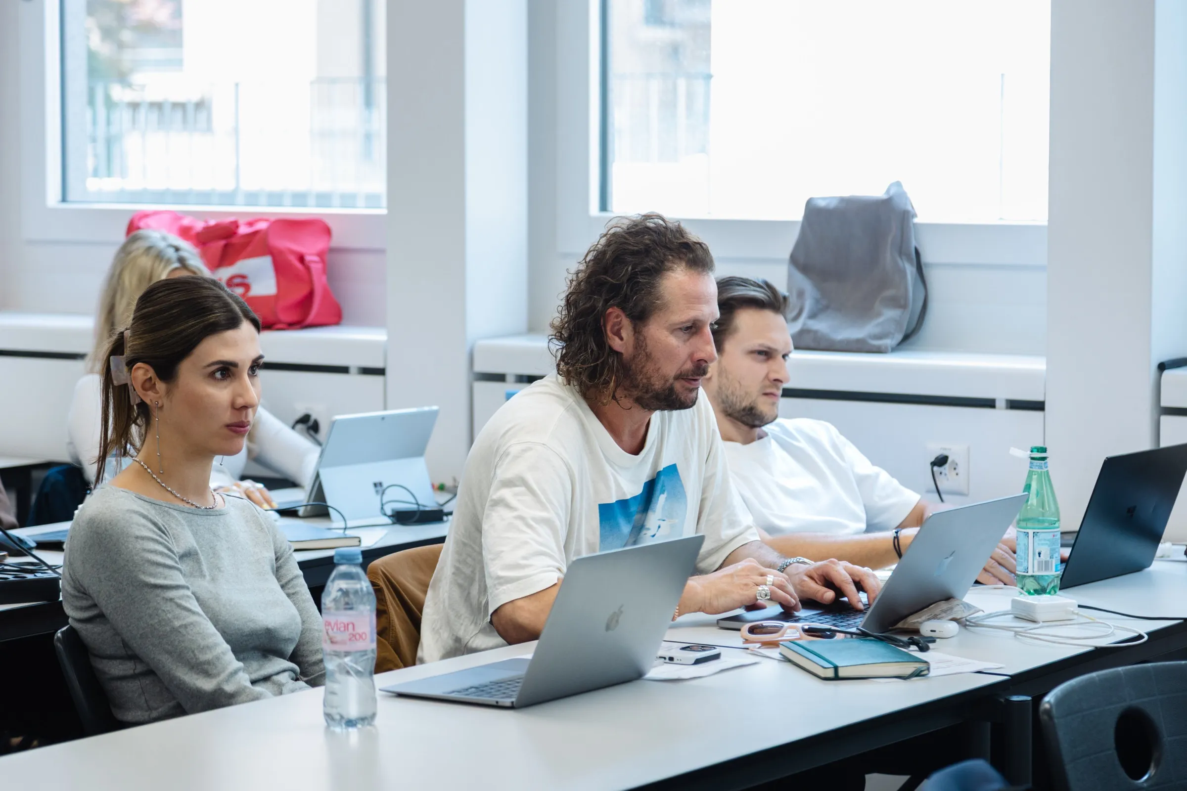 Three participants working on their laptops in the classroom